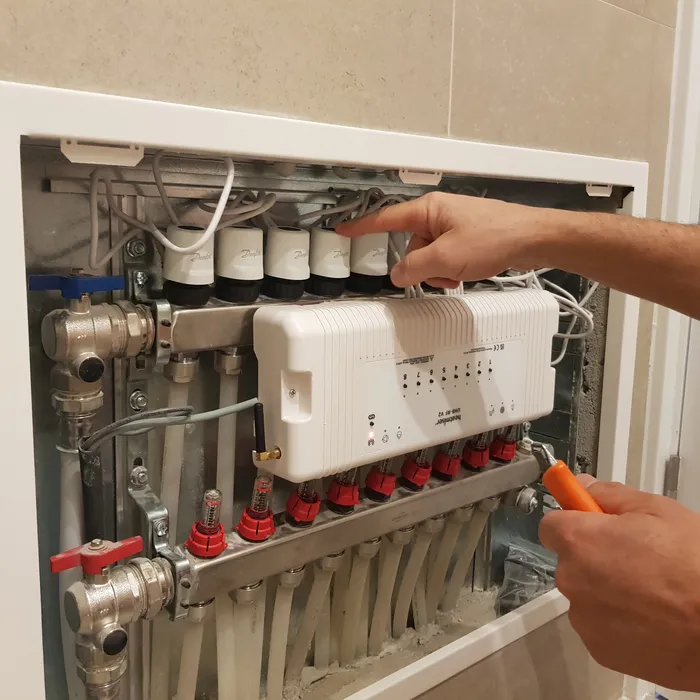 Close-up of a heating manifold and actuators being adjusted