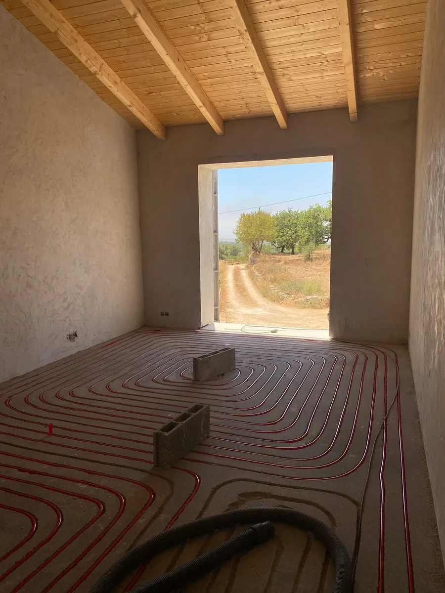 Milled channels and pipework in a rustic villa with exposed wood-beam ceiling