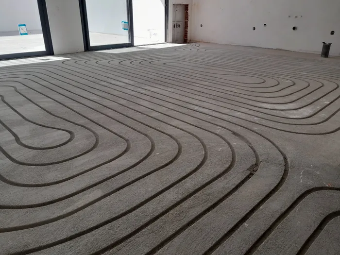 Wide shot of a dense serpentine pipe circuit laid across a screed floor