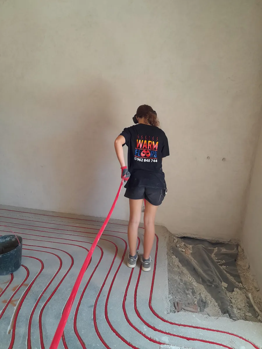 A team member finishing a heating pipe run on site, wearing the team's Warm Floors work shirt