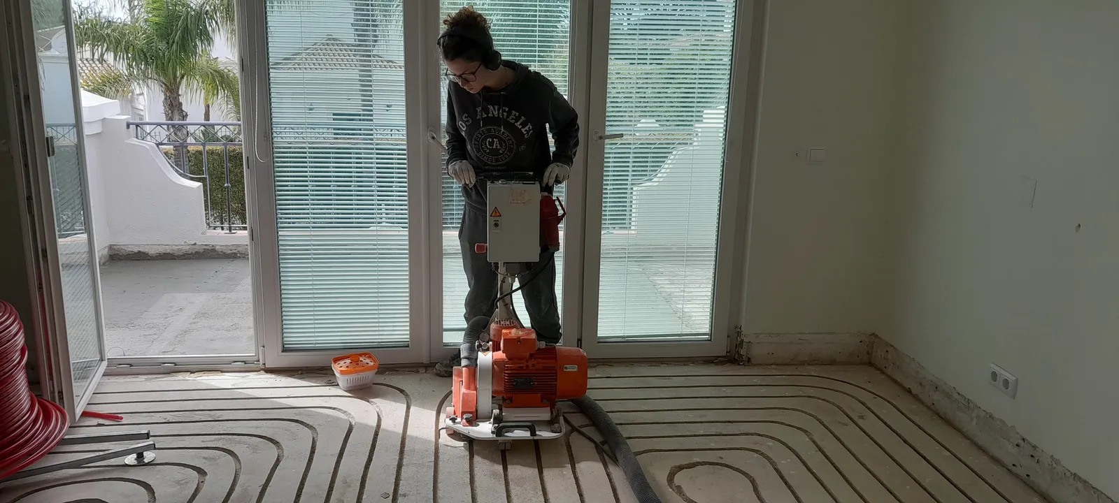 A team member operating the milling machine beside a villa glass doors